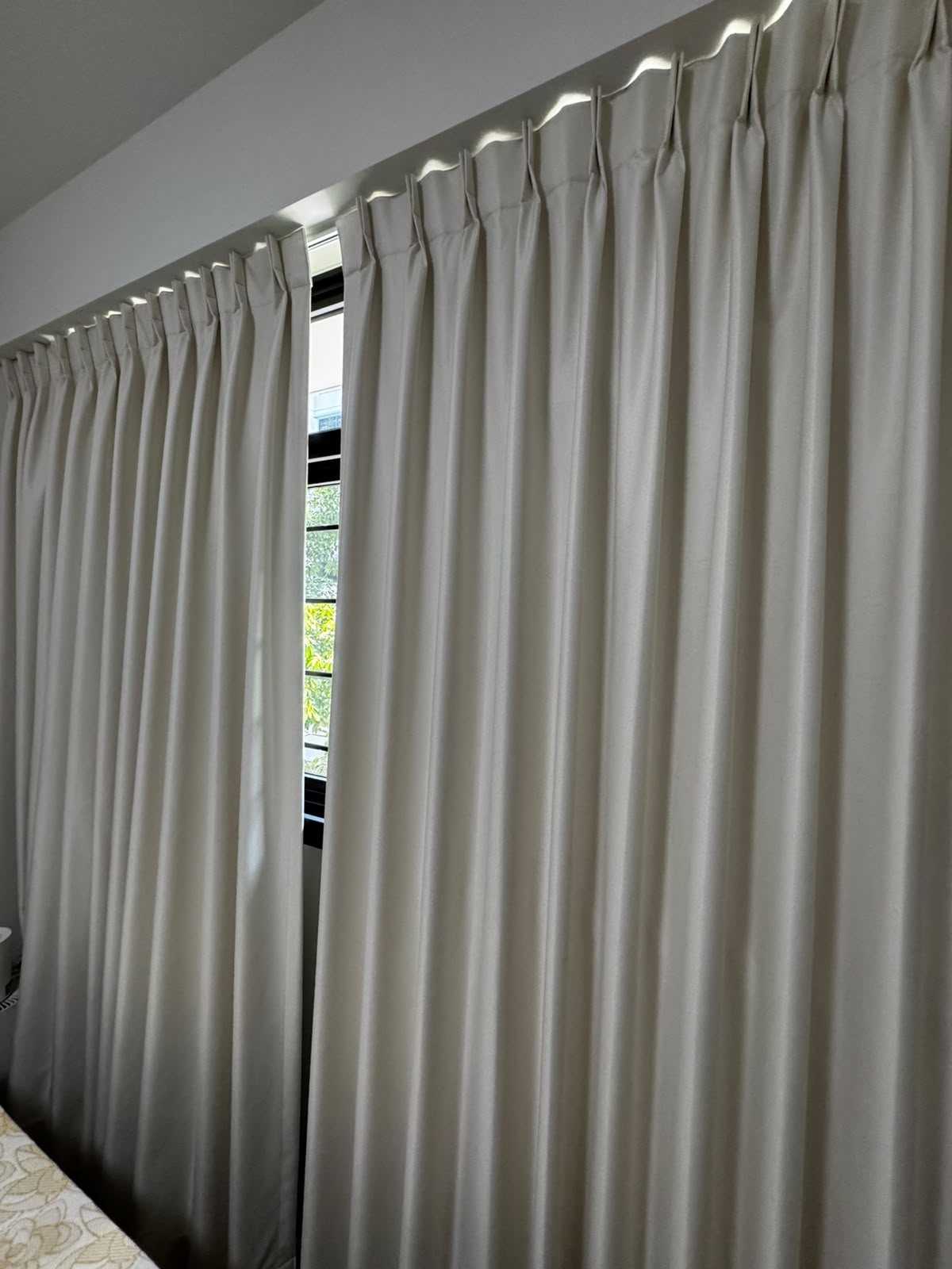 Neutral curtain installation in a bright bedroom